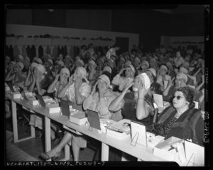 Audience of women applying makeup at lecture by beautician Manka Rubenstein in Los Angeles, Calif., circa 1950